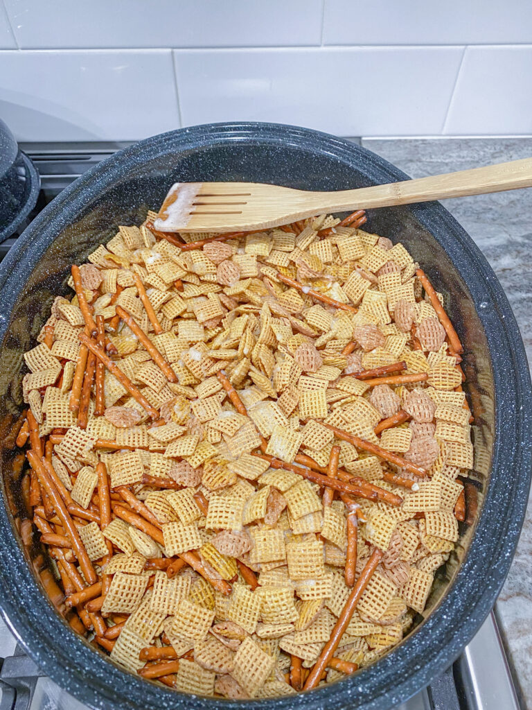 Stirring the party mix with a wooden spoon.